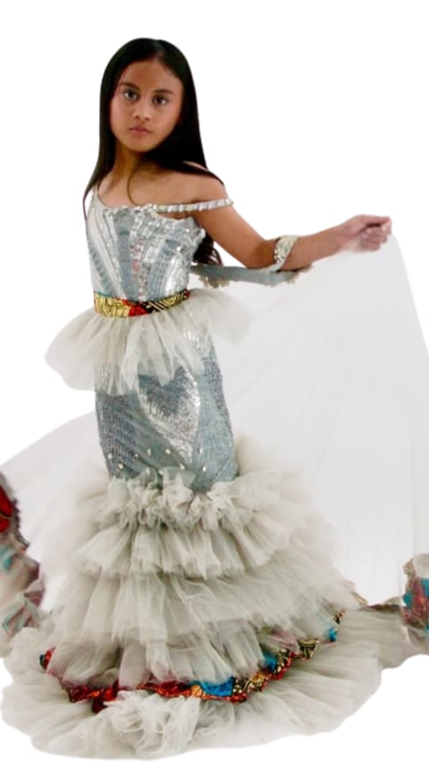 Young girl in an elaborate white and silver sequined mermaid-style gown with gold belt