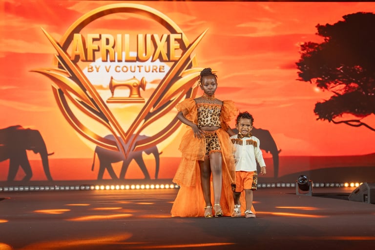 Two children on stage with an African savanna backdrop and ornate golden Aapluxe logo behind them at sunset