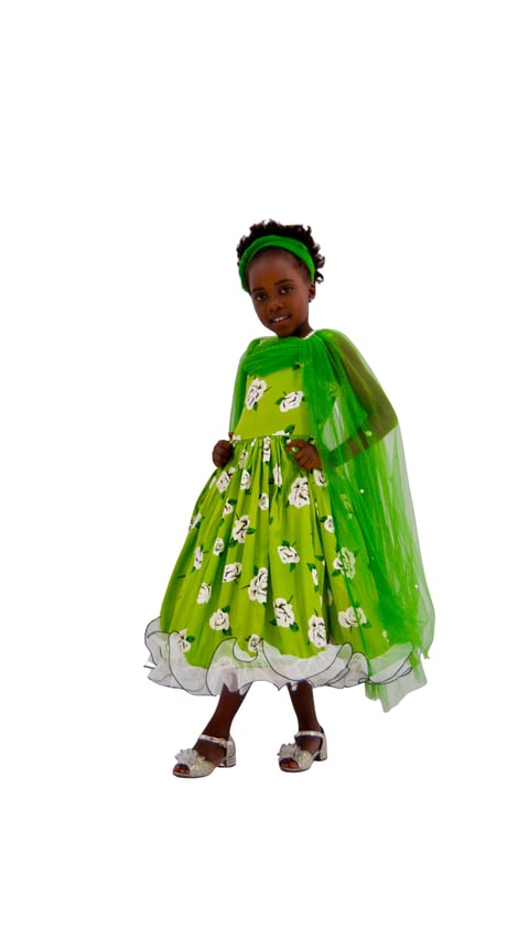 Young child wearing a bright green princess dress with floral pattern and matching cape, headband, and accessories, smiling at camera