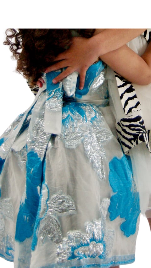 Child wearing blue and silver floral dress with puffed sleeves, viewed from above