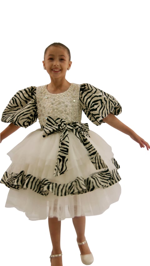 Young child wearing a zebra-striped puff sleeve dress with a cream tulle skirt and matching bow belt