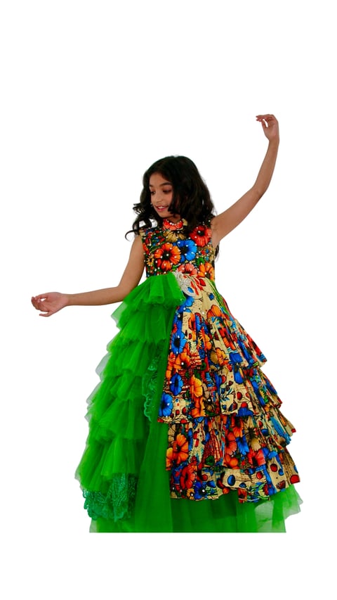 Woman in colorful floral African print dress with bright green layered tulle skirt, arms raised in celebratory pose