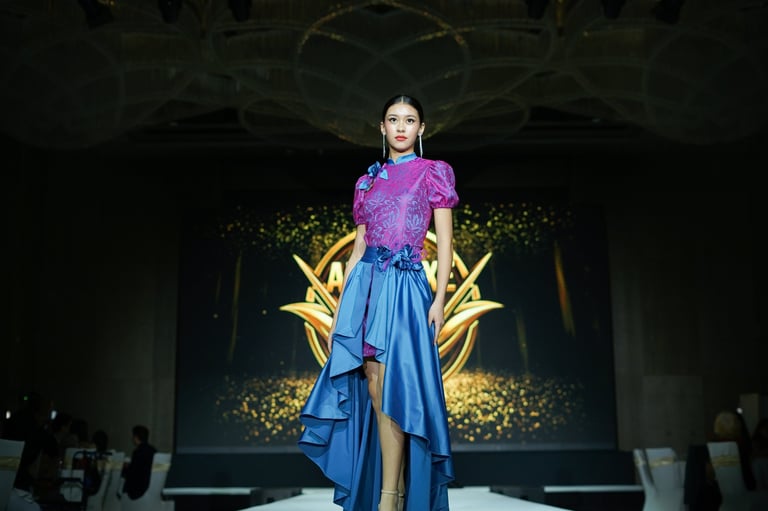 Model on runway wearing purple sequined top with blue asymmetrical skirt against illuminated gold lightning bolt backdrop